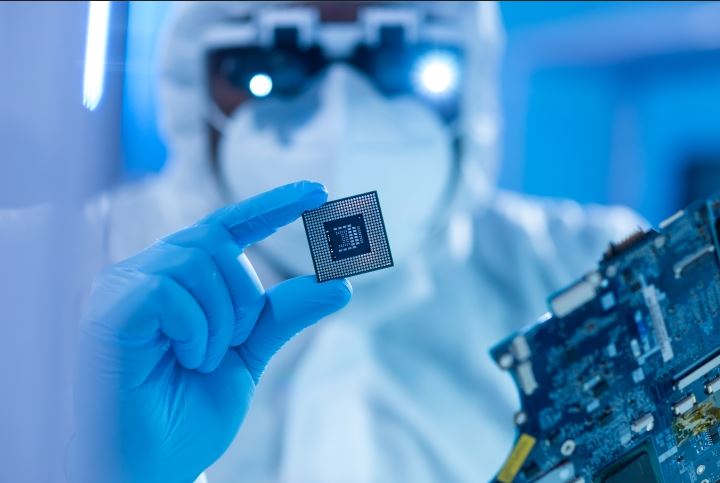Das Bild zeigt einen Reinraummitarbeiter mit einem Chip in der Hand.