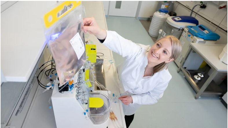Im Biologischen Labor: Alexandra Kegler steht vor einem Gerät und greift nach einer in einem Beutel befindlichen klaren Flüssigkeit.
