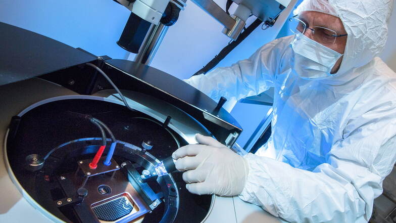 Ein Mann in weißer Schutzkleidung stellt in einem sterilen Raum einen Chip her.