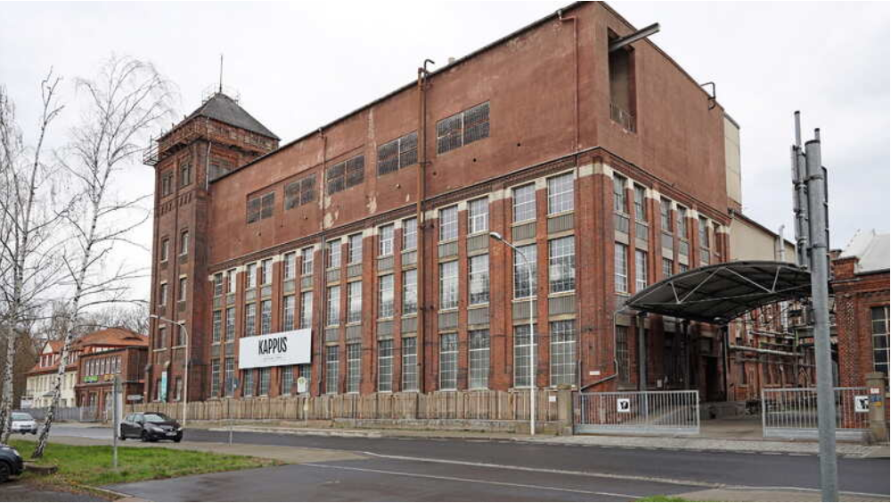 Ein altes Werksgebäude mit brauner Fassade und sechs Etagen.