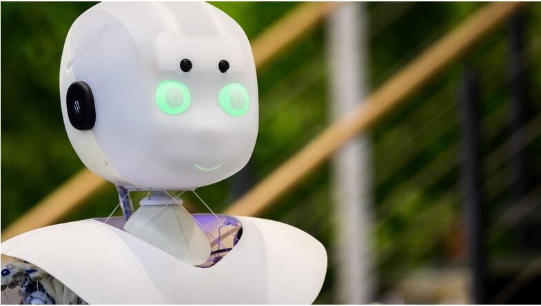 Ein ferngesteuerter, weißer Roboter mit grünen Leucht-Augen strahlt in die Kamera