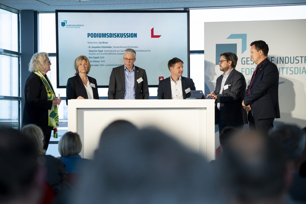 Das Bild zeigt mehrere Menschen hinter einem Podium beim Fortschrittsdialog.