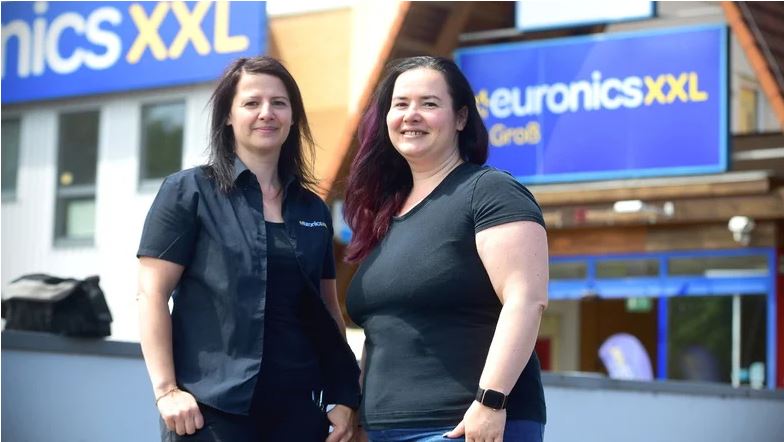 Manuela und Steffi (r.) Groß haben die Geschäftsführung des "Euronics"-Elektronikmarkts von ihrem Vater übernommen und stehen lächeln nebeneinander.