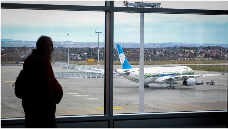 Man sieht aus einem Flughafenfenster einen Flieger.