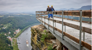 Man sieht Arbeiter auf einer Betonbrücke über der Elbe.