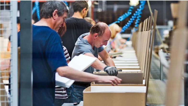 Man sieht Menschen, die Kartons einpacken.
