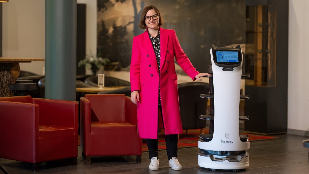Eine Frau steht neben einem Roboter im Hotel.