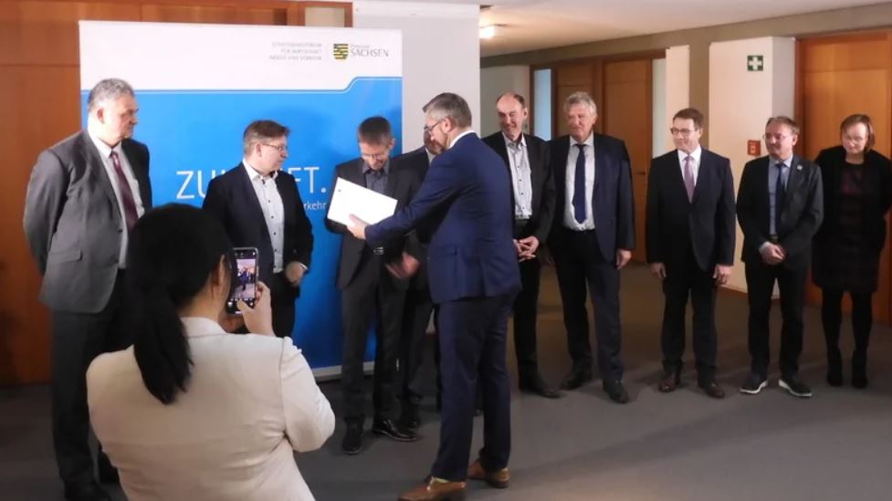 Man sieht Wirtschaftsminister Martin Dulig hat einen Fördermittelbescheid an Infineon und Partnerfirmen übergeben.