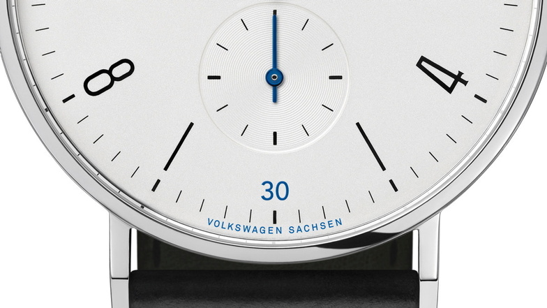 Man sieht die Abbildung einer Uhr von Nomos Glashütte, drauf steht der Name der Firma Volkswagen Sachsen.