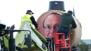 Landwirte befestigen ein Portrait von Umweltminister Wolfram Günther (Grüne) an einer Strohfigur.