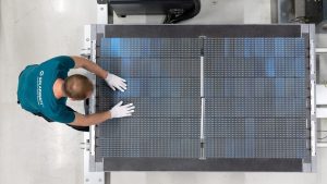 Man sieht einen Mitarbeiter mit einer Solarzelle