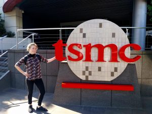 Eine junge Frau steht vor dem Logo der Firma TSMC.