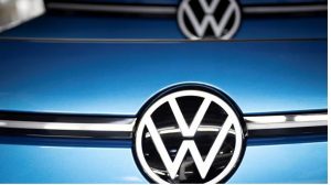 Man sieht eine blaue Motorhaube mit VW-Logo.