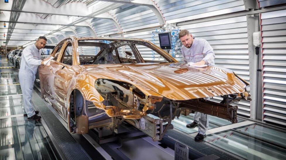 Man sieht Porsche-Mitarbeiter bei der Qualitätskontrolle des Fahrzeugs.