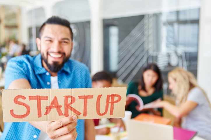 Ein Mann zeigt ein Schild mit dem Wort "Start-up".