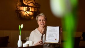 Man sieht Kathrin Scholz vom "Dresdner Hof" in Zittau mit der Speisekarte von ihrem Restaurant