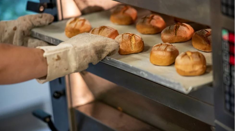 Man sieht einen Bäcker beim Brötchen backen