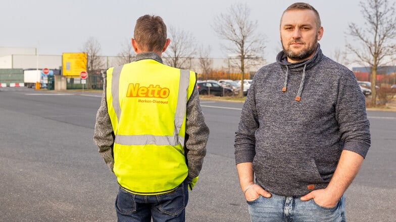 Zwei Männer stehen nebeneinander. Der eine Mann trägt eine Netto-Warnweste und steht mit dem Rücken zur Kamera. Der andere Mann schaut ernst in die Kamera.