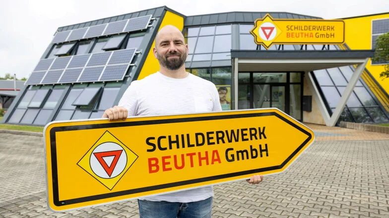 Mann hält ein Schild in Pfeilform.