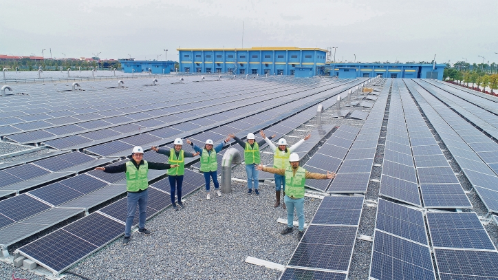 Mehre Menschen stehen auf einem mit Solarpanelen bestückten Dach.
