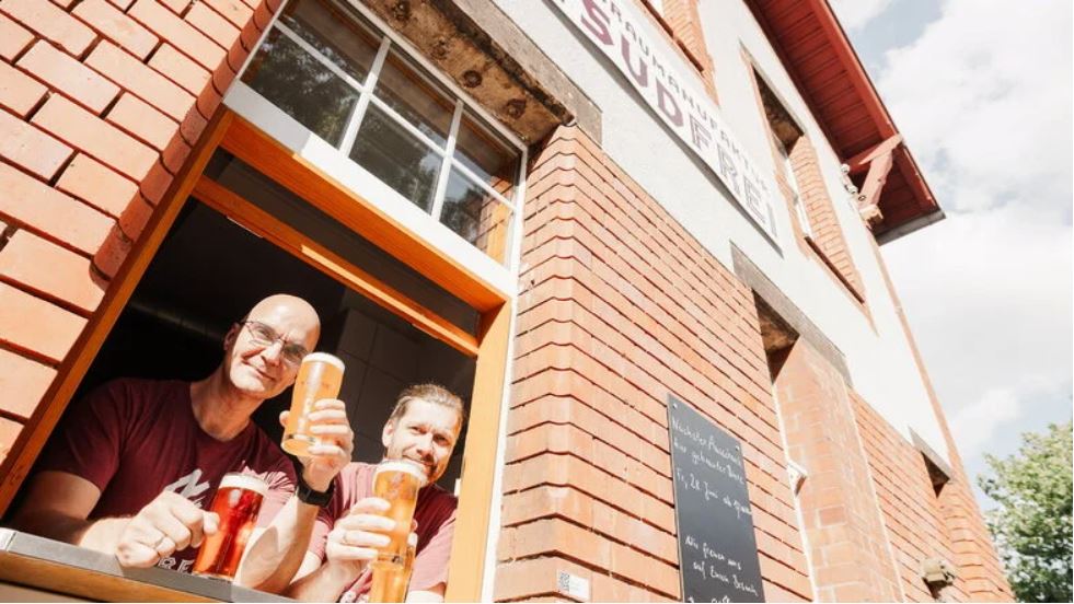 Man sieht Markus Morawietz und Falk Beuchel am Fenster beim Bier trinken