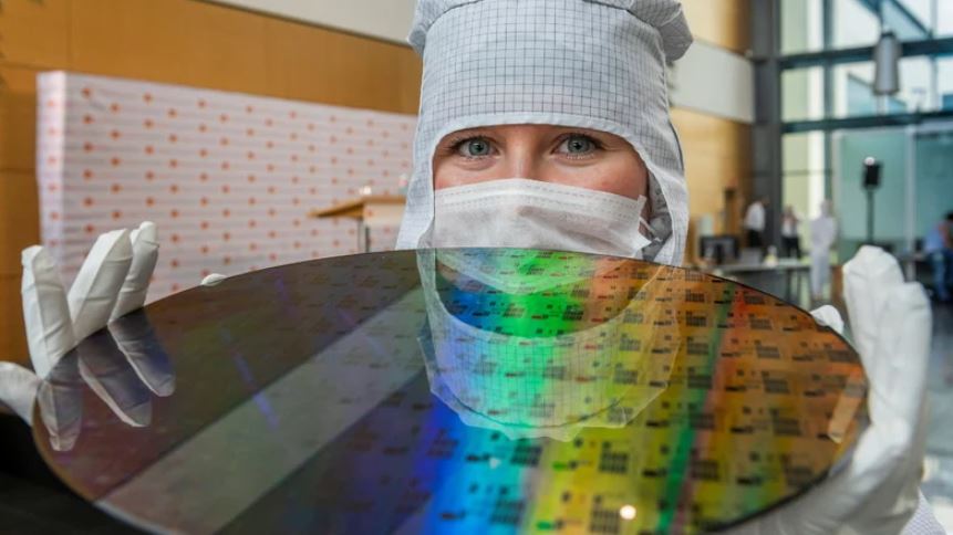 Man sieht eine Azubi, die einen Wafer für Halbleiter präsentiert