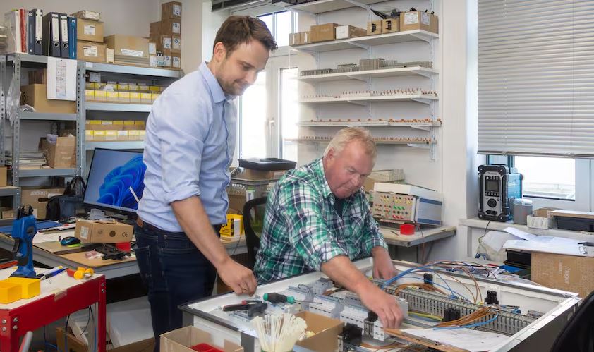 Man sieht Geschäftsführer Maik Stamm und Lutz Töpfer, der einen Schaltschrank baut