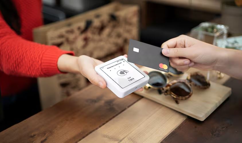 Man sieht eine Person, die die Bankkarte an dem Kartenlesegerät hält