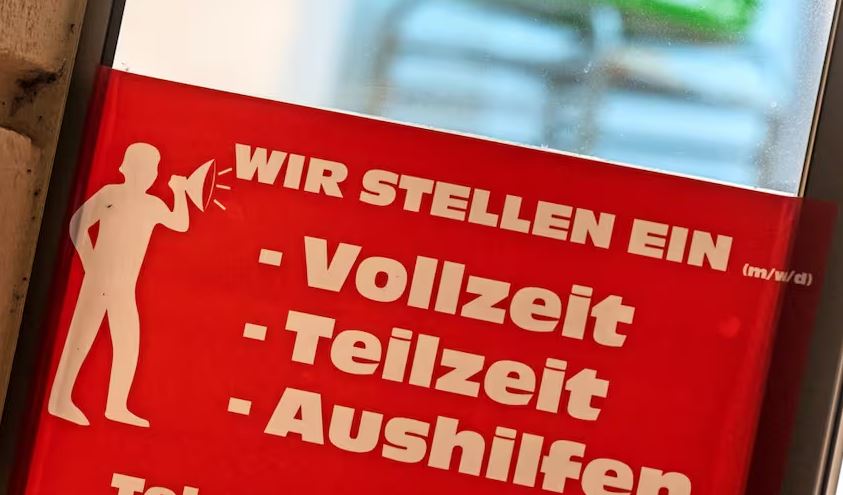 Ein Schild mit der Aufschrift „Wir stellen ein – Vollzeit, Teilzeit, Aushilfen“ hängt am Eingang einer Bäckerei.
