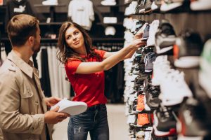 Eine Verk&auml;uferin zeigt einem Kunden Schuhe.