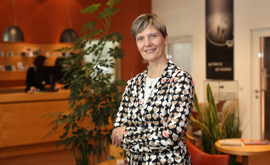 Eine Frau schaut freundlich in die Kamera.