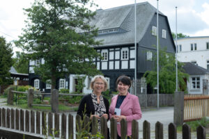 Zwei Frauen stehen vor einem Umgebindehaus.