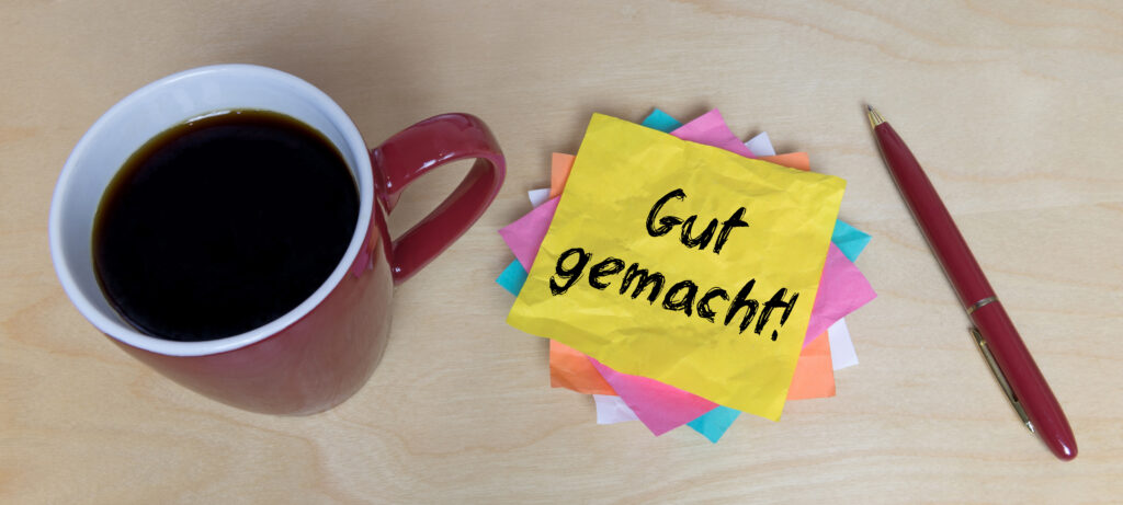 Eine Kaffeetasse,ein Stift und ein Zettel liegen auf einem Tisch.