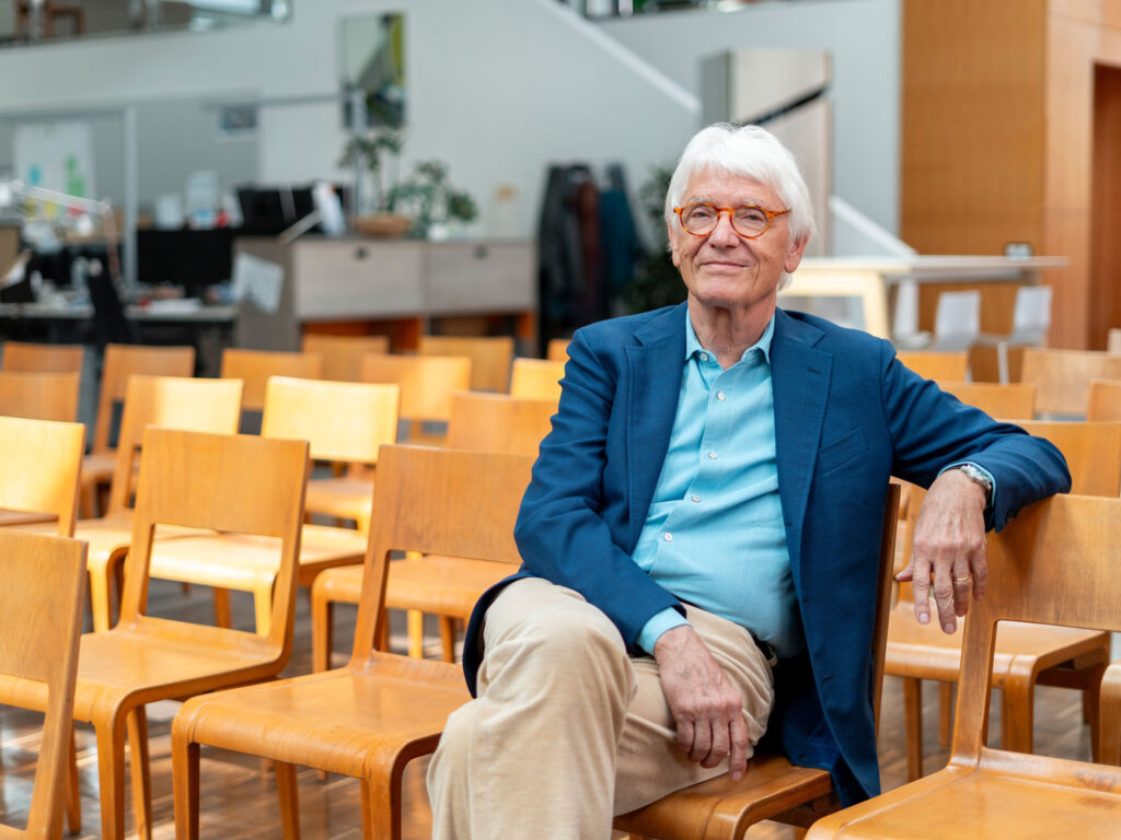 Ein Mann sitzt auf einem Stuhl und schaut in die Kamera.