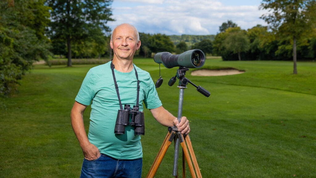 Ein Mann steht mit Fernglas auf einem Goldplatz.