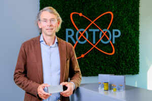 Ein Mann steht vor einem Bildschirm mit Logo.