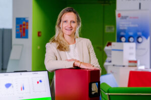 Eine Frau steht lächelnd in ihrem Büro.