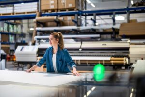 Eine Frau steht an einer Papierschneidemaschine.