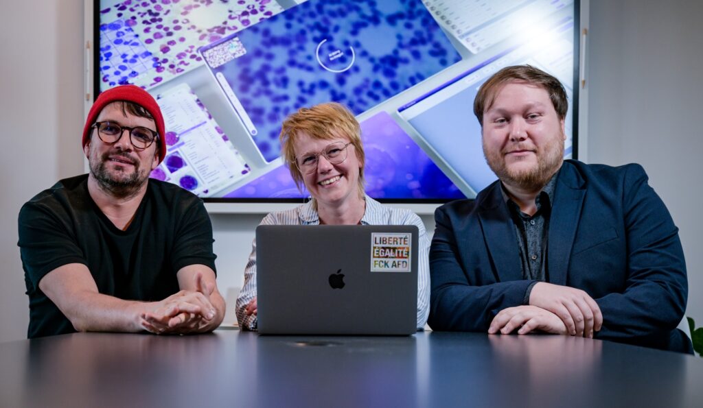 Drei Menschen schauen freundlich in die Kamera.