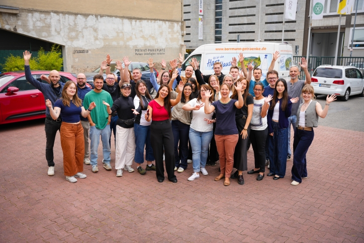 Eine Gruppe Menschen schaut erfreut in die Kamera.