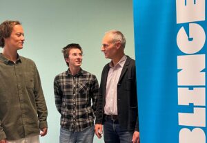 Drei Menschen stehen neben einem Aufsteller der Joblinge.