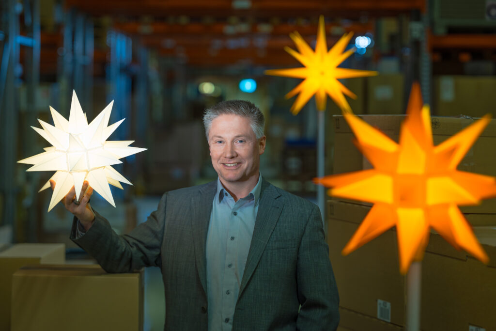 Ein Mann steht zwischen Herrnhuter Sternen.