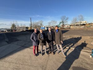 Mehrere Menschen stehen vor einer Baufl&auml;che.