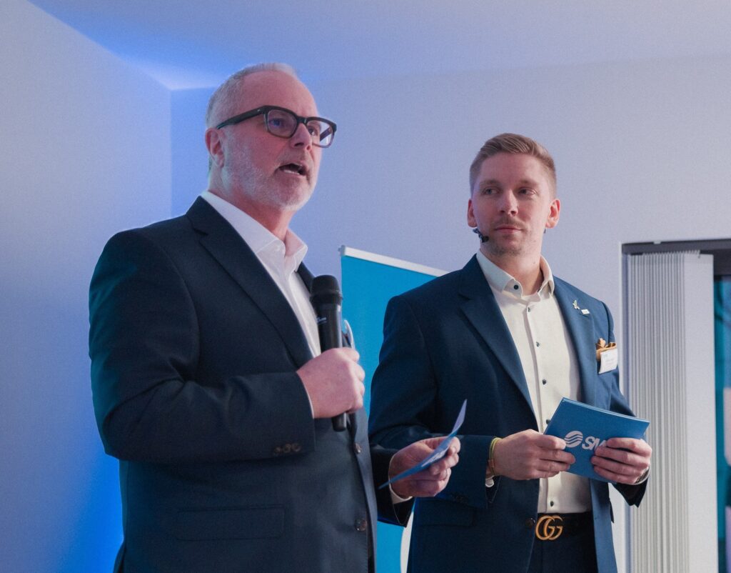 Zwei M&auml;nner stehen auf einem Podium.