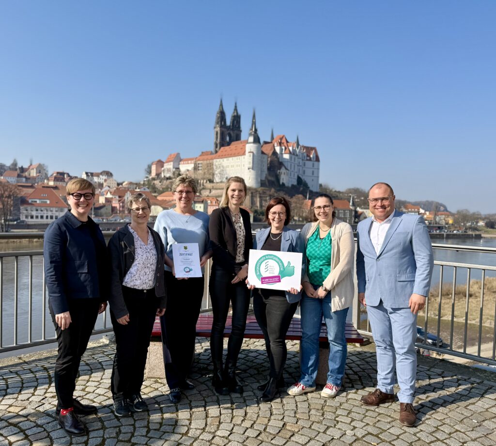 Eine Gruppe Menschen schaut freudig in die Kamera.