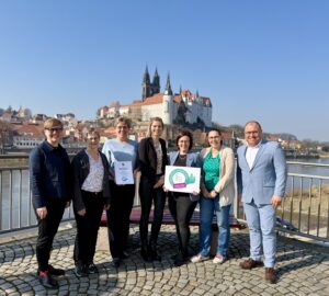 Eine Gruppe Menschen schaut freudig in die Kamera.