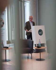 Thomas de Maizière am Rednerpult mit SAB-Logo. Im Hintergrund ein Aufsteller mit Hinweisen zu Förderprogrammen.