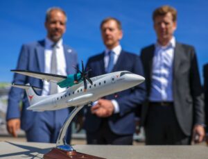 Drei M&auml;nner stehen hinter einem Modell eines Flugzeugs.