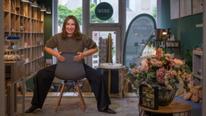 Eine Frau sitzt in ihrem Atelier auf einem Stuhl