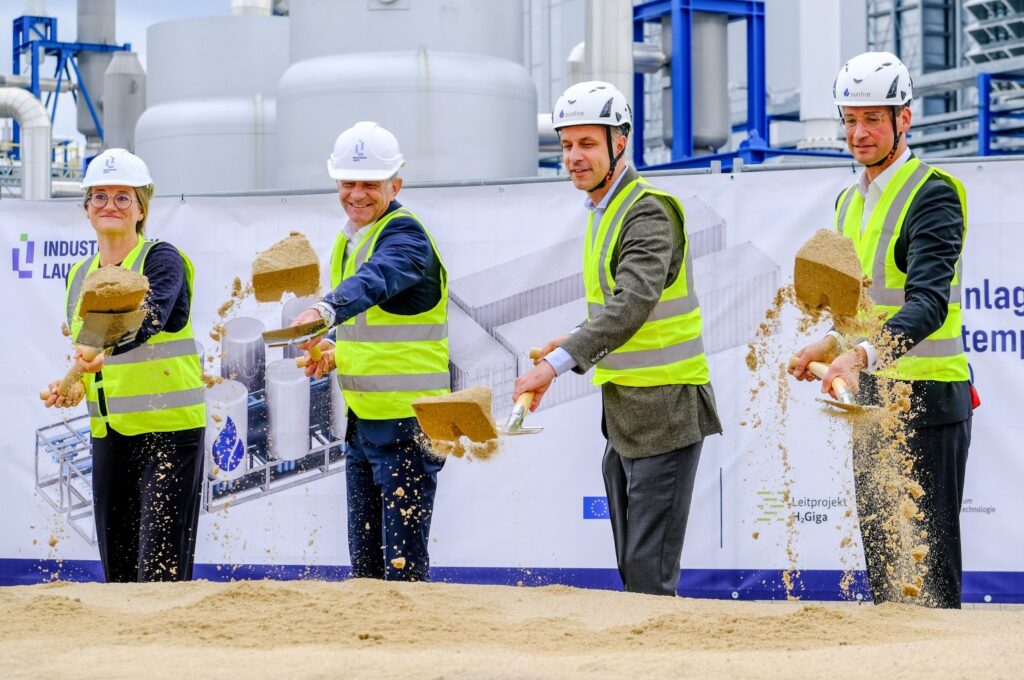 Vier Menschen schippen Sand